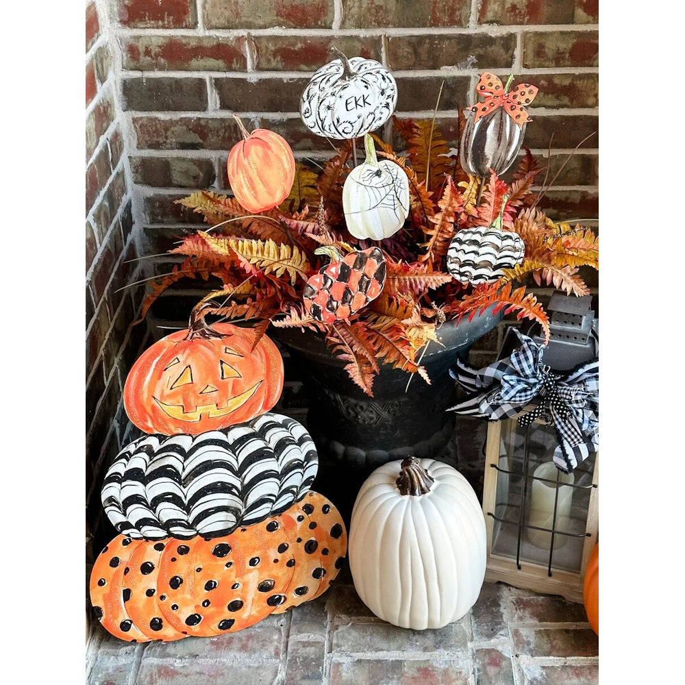Halloween porch display with a jack-o'-lantern stack sign, white pumpkin, lantern, and patterned accents.