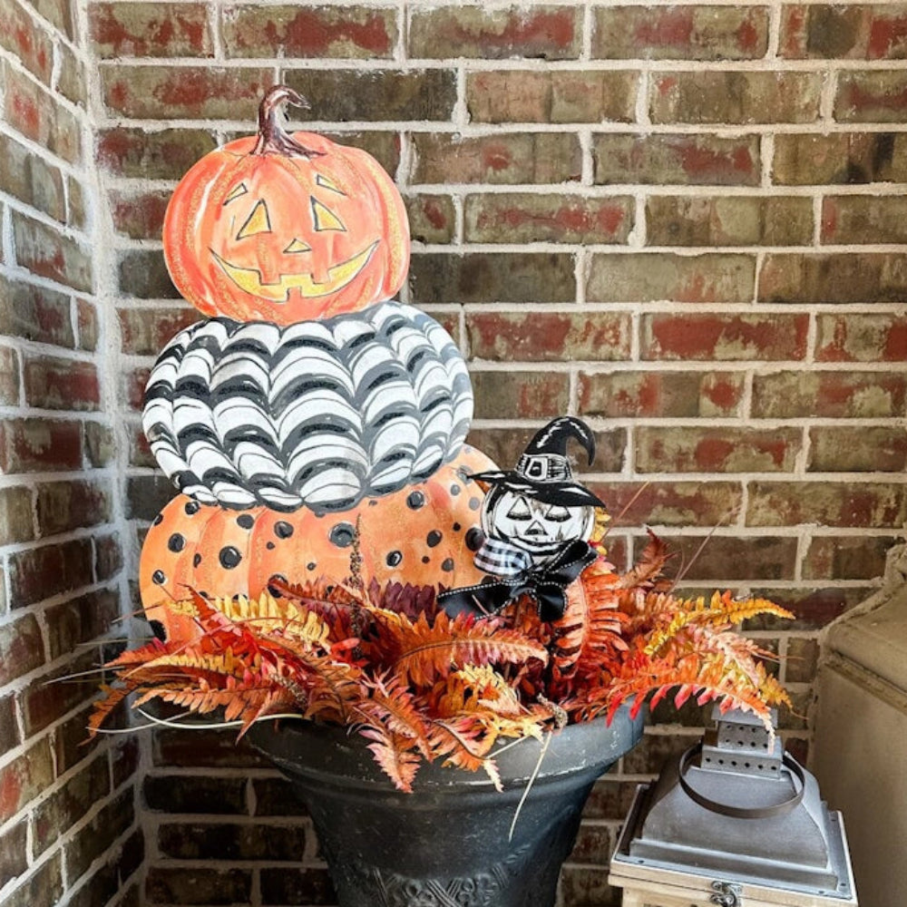 Halloween porch planter with a stacked jack-o'-lantern sign, fall leaves, and a witch-hat pumpkin.