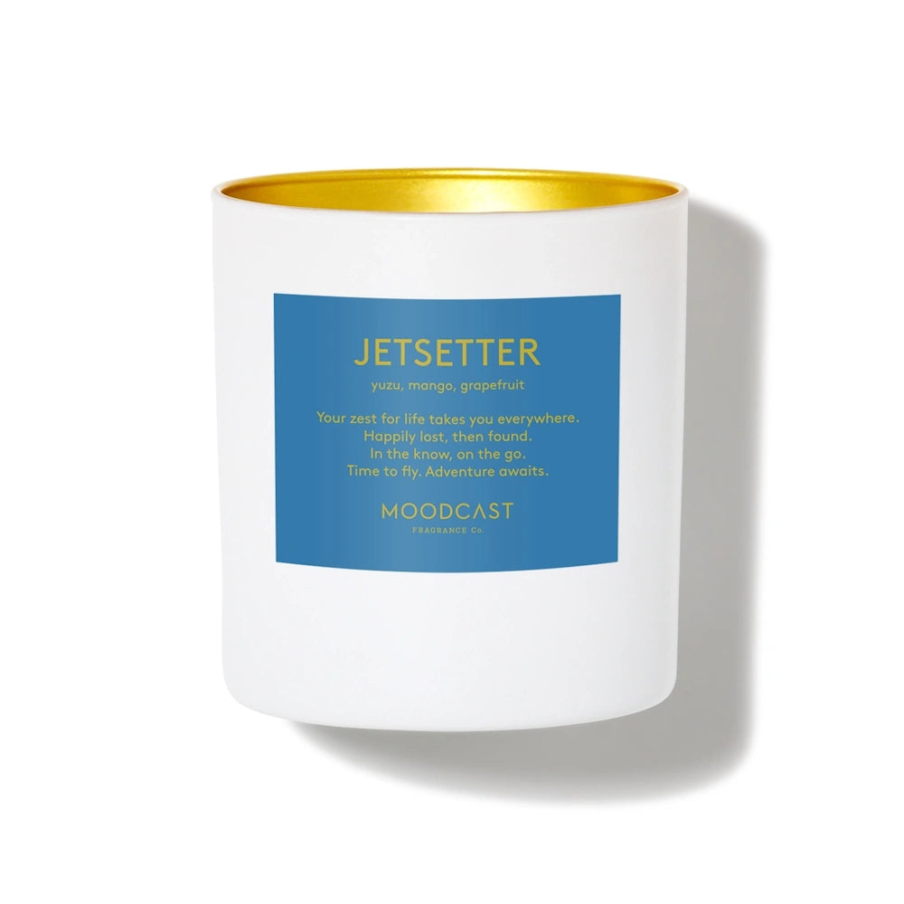 White Moodcast Jetsetter scented candle with a blue label and gold interior on a white background.