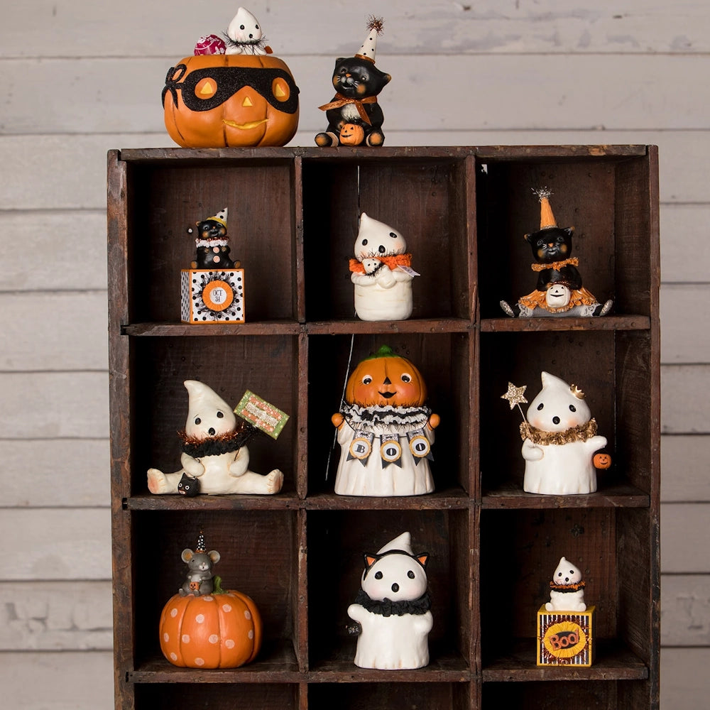 Wooden shelf filled with vintage Halloween figurines including ghosts, black cats, and pumpkin decorations.