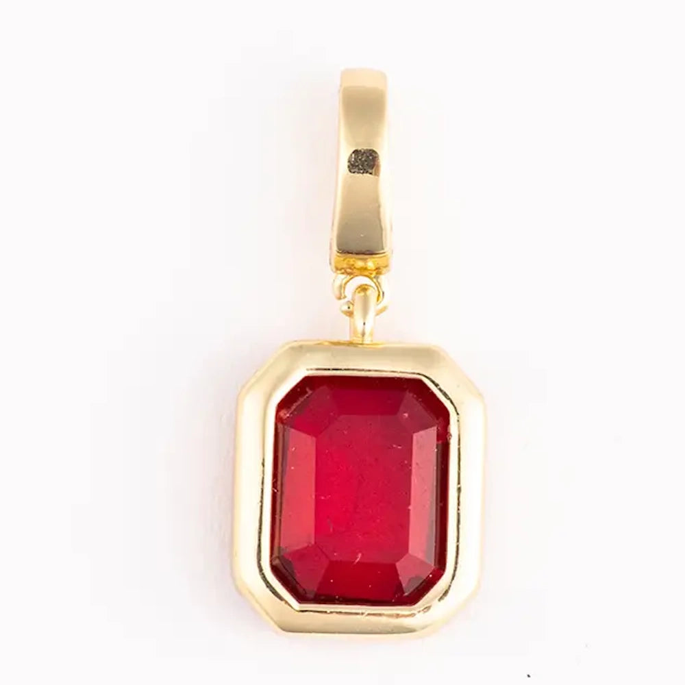 Gold pendant charm featuring an emerald-cut red gemstone set in a thick gold bezel.