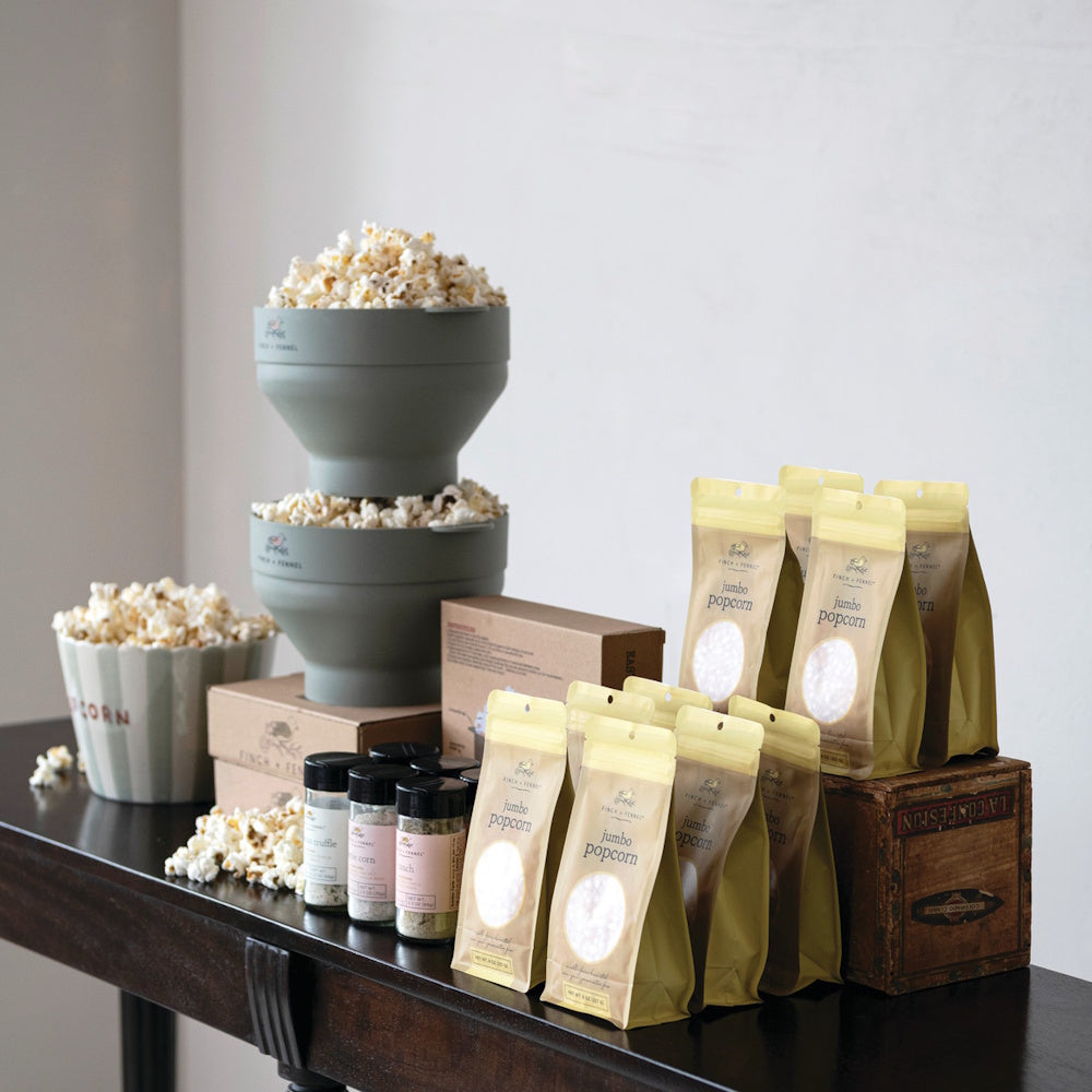 Finch + Fennel jumbo popcorn bags, seasonings, and stacked silicone poppers overflowing with popcorn.