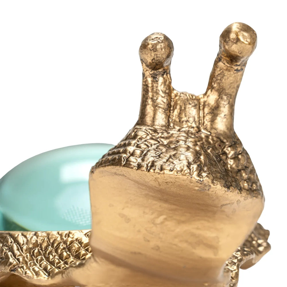 Close-up of a textured gold snail head with extended eyestalks and a magnifying lens behind it.