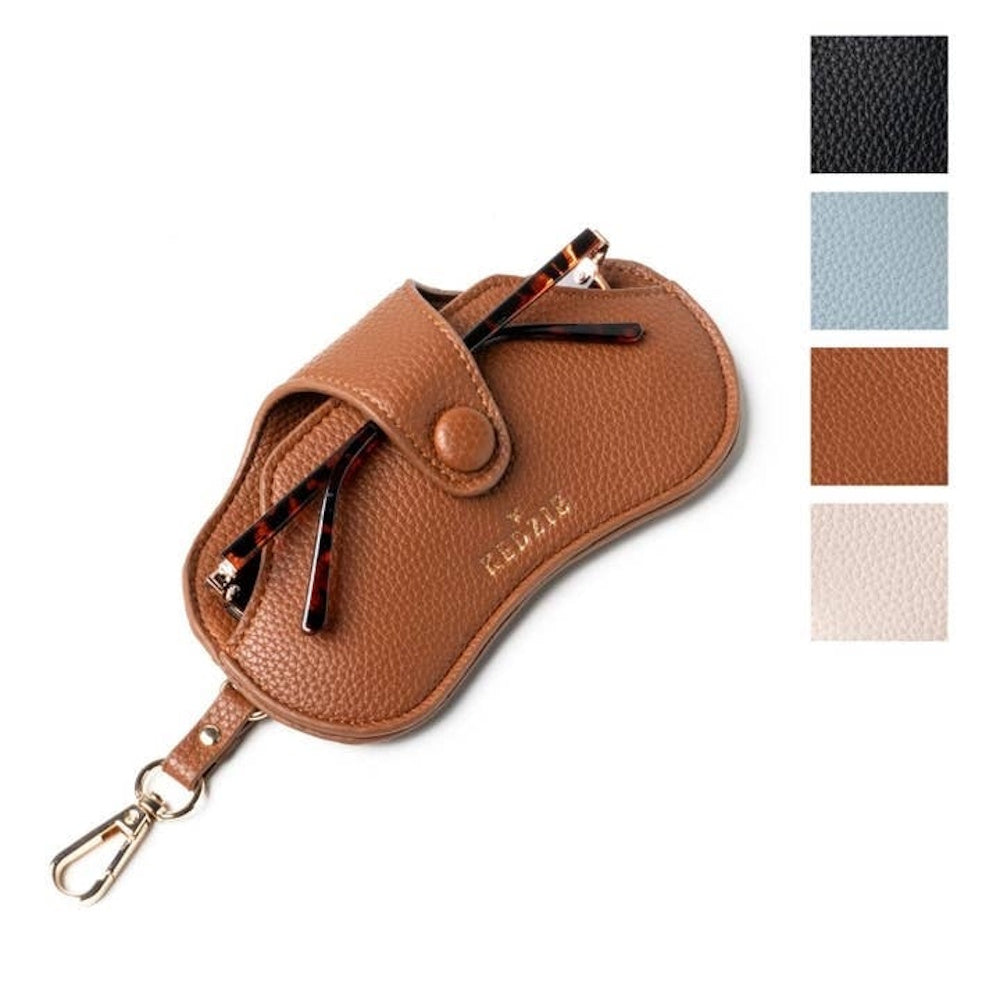 Brown pebbled leather Kedzie eyewear case with gold hardware, holding tortoiseshell glasses. Multiple color swatches shown.