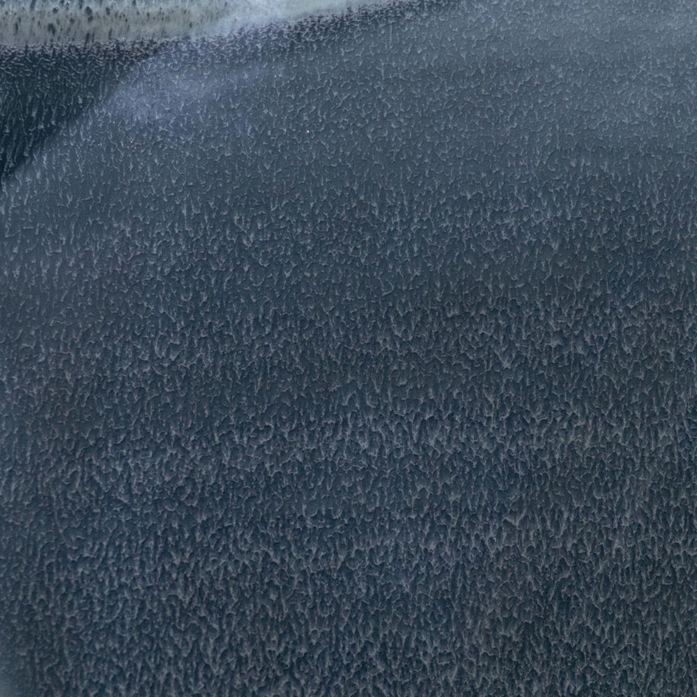 Detailed texture shot of charcoal gray reactive glaze on a ceramic surface, showing a fine speckle and matte finish.