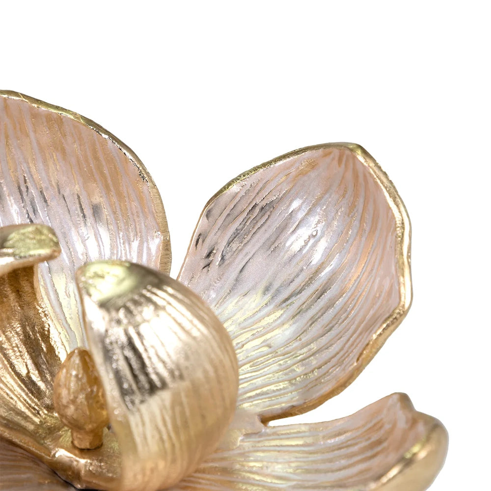 Close-up of a metallic flower sculpture featuring iridescent pink petals with gold edges and a gold center.