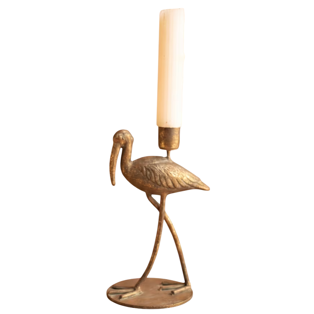 Large antique brass shorebird taper candleholder holding a white candle on a white background.
