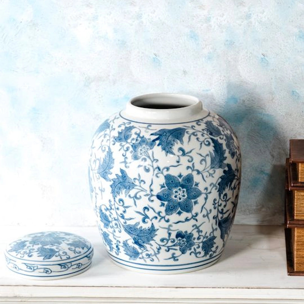 Large blue floral porcelain ginger jar with lid on a white shelf against a textured light blue wall.