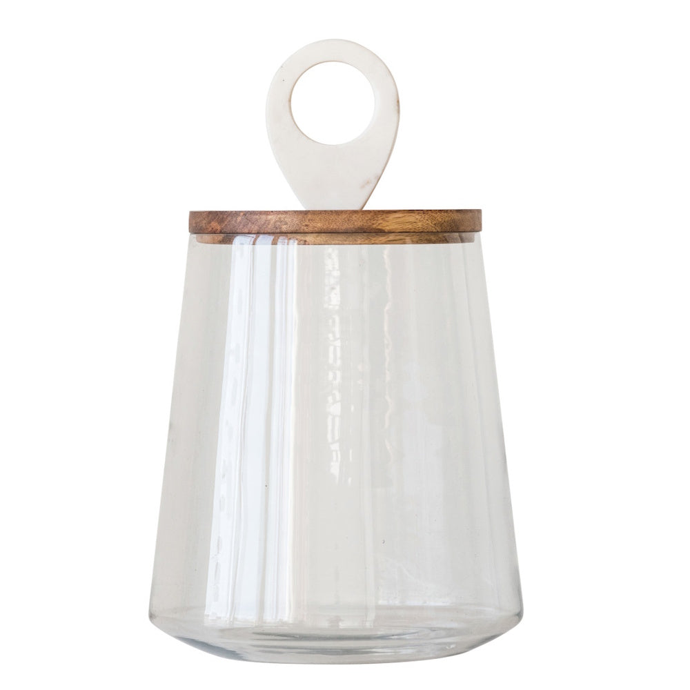 Clear, tapered glass storage jar with a flat wooden lid topped by a white marble ring handle.