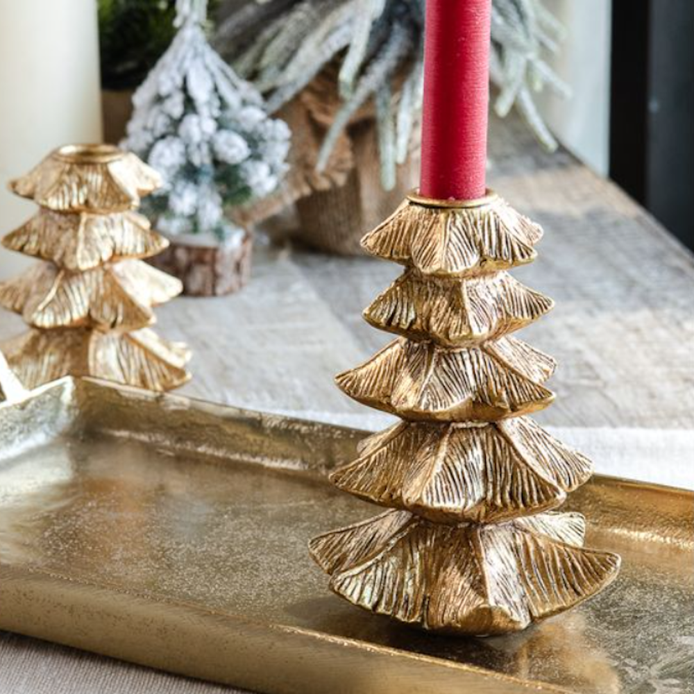 Tall gold tree taper candle holder with a red candle resting on a metallic tray.