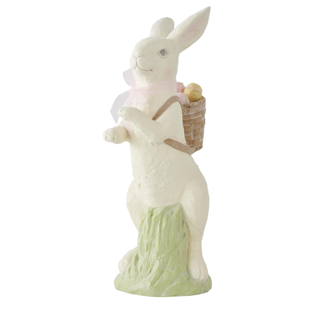 White resin Easter bunny figurine with a pink bow and a basket of eggs on its back, standing on a green base.