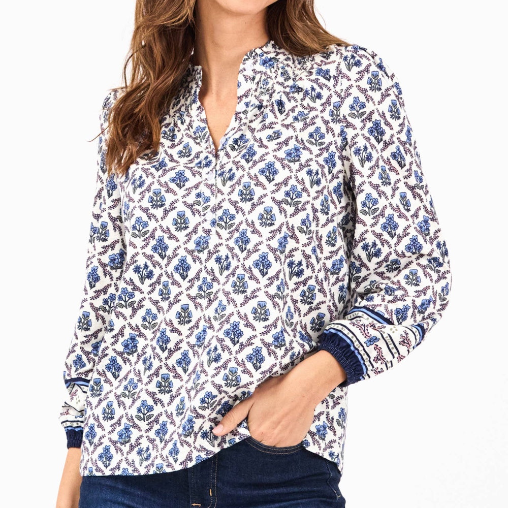White long-sleeve blouse with blue and purple floral lattice print, split neckline, and fitted cuffs.