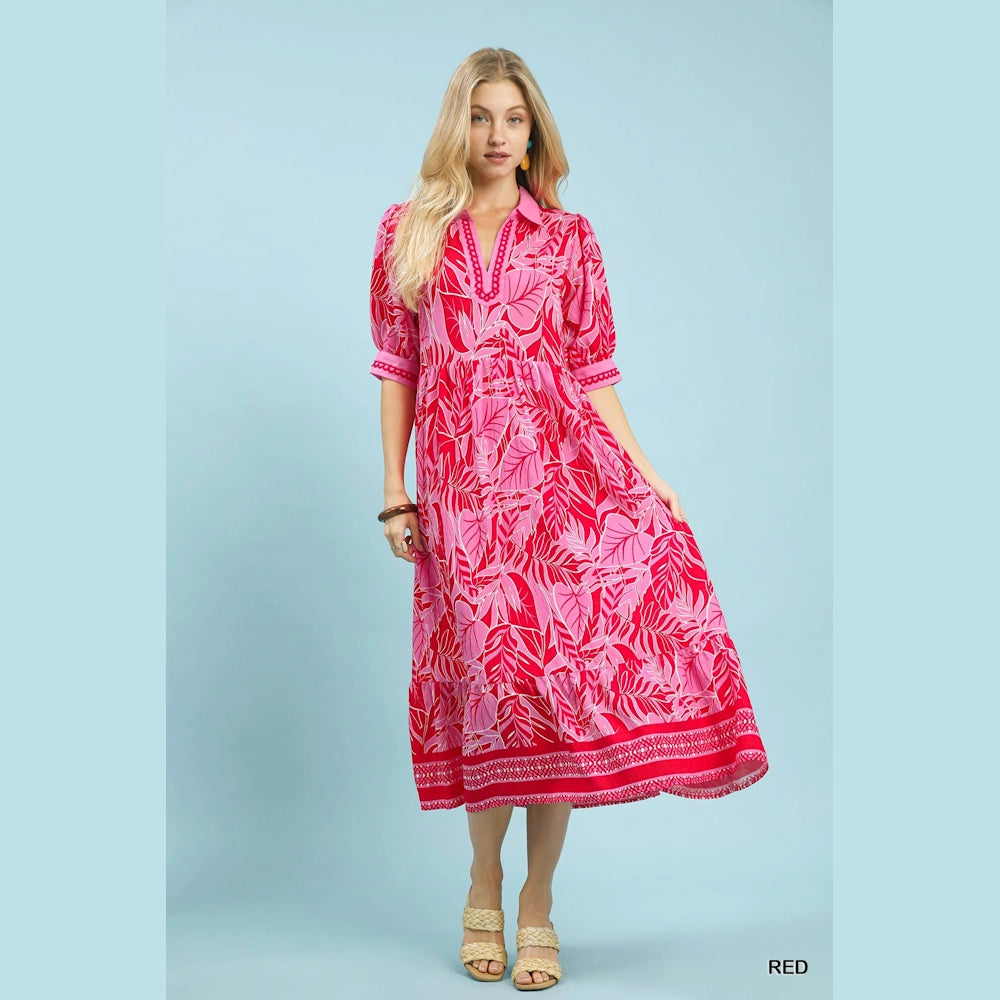Woman in a pink and red leafy print v-neck midi dress with puff sleeves and a patterned border hem.