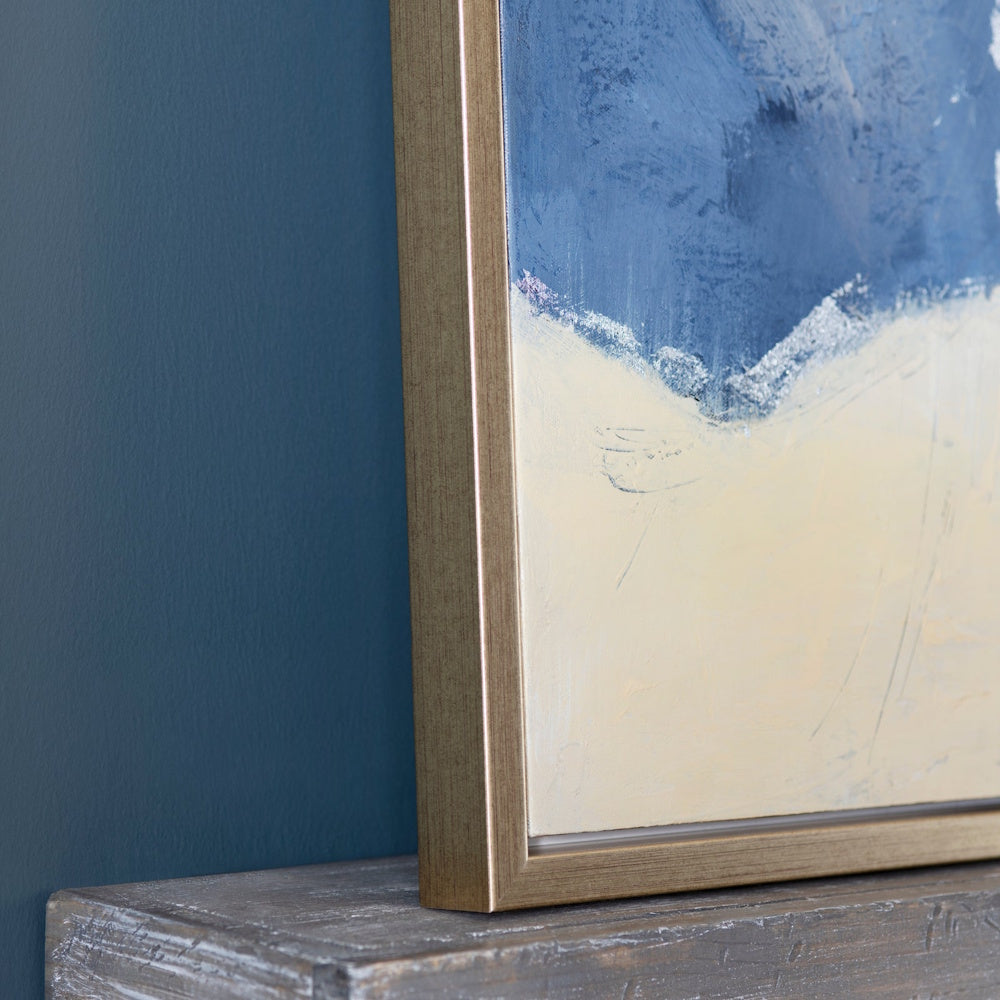 Framed blue and cream abstract painting on a rustic wooden shelf against a dark teal wall.