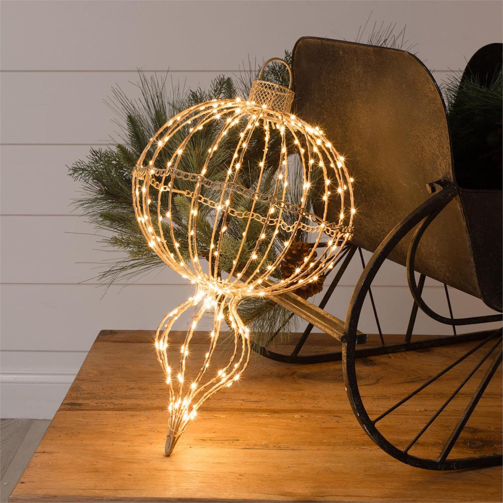 Illuminated wire finial ornament display piece with warm fairy lights, resting next to a sleigh.
