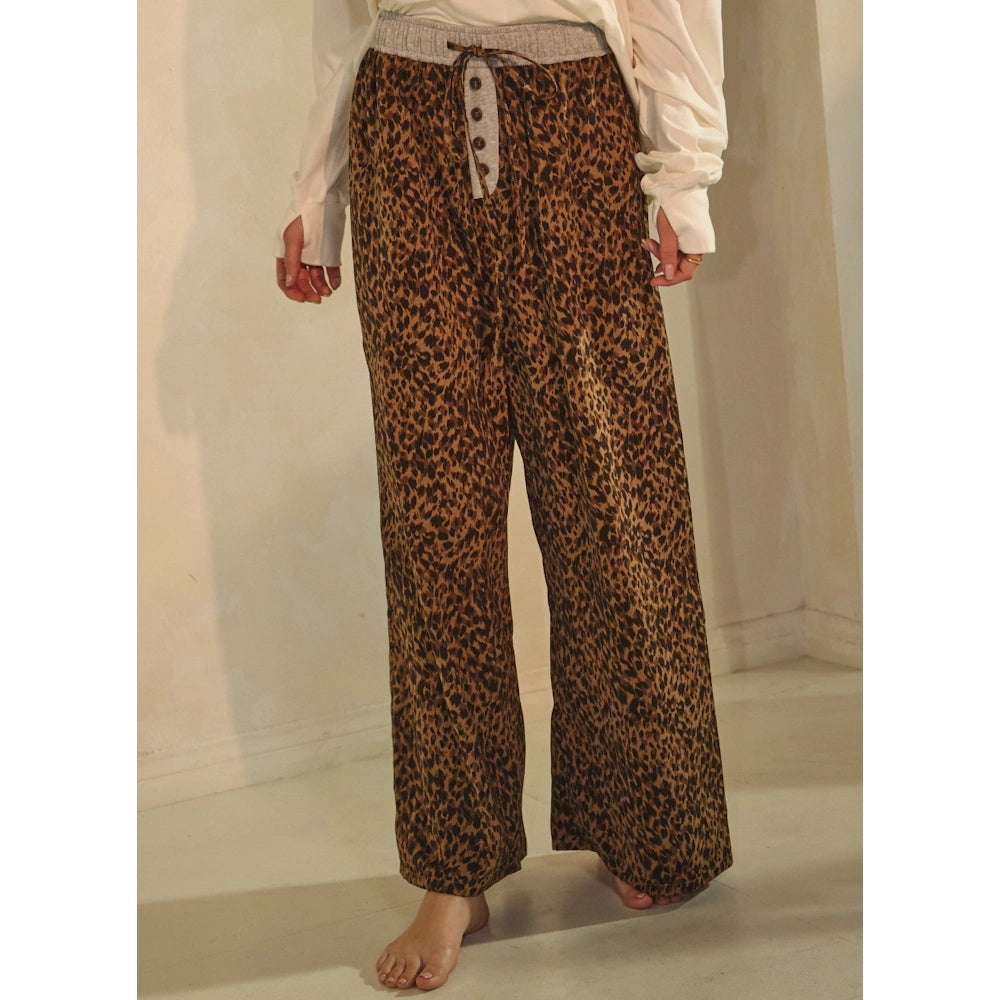 Front view of leopard-print wide-leg lounge pants with a gray ribbed waistband, drawstring, and button fly.