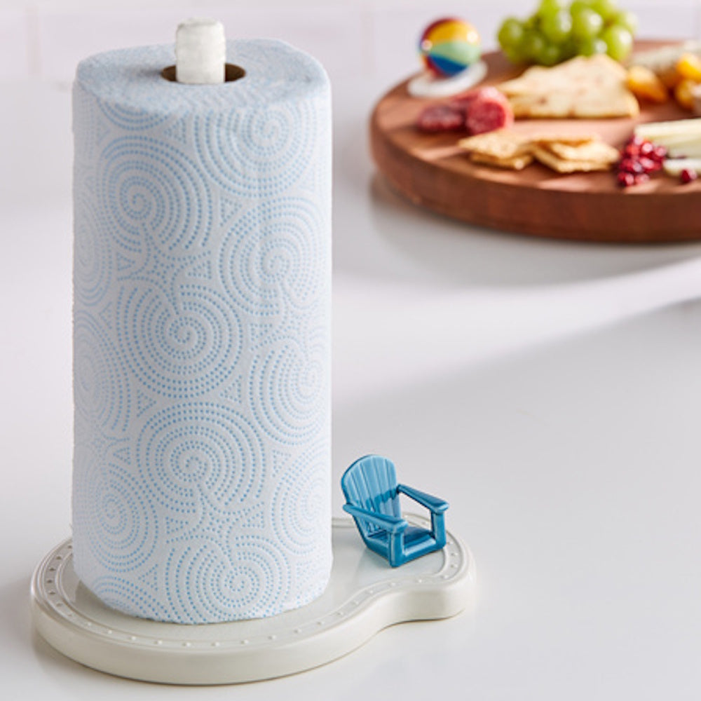 A roll of blue patterned paper towels on a stand featuring a small blue Adirondack chair figurine.