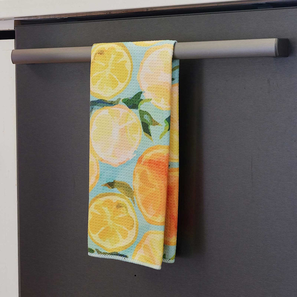 Lemon slice patterned tea towel hanging on a modern dark gray oven handle in a kitchen.