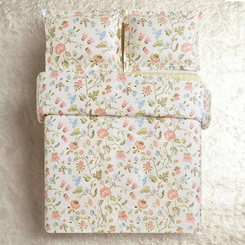 Floral bedding set with pink and blue botanical print comforter and matching pillows on a white background.
