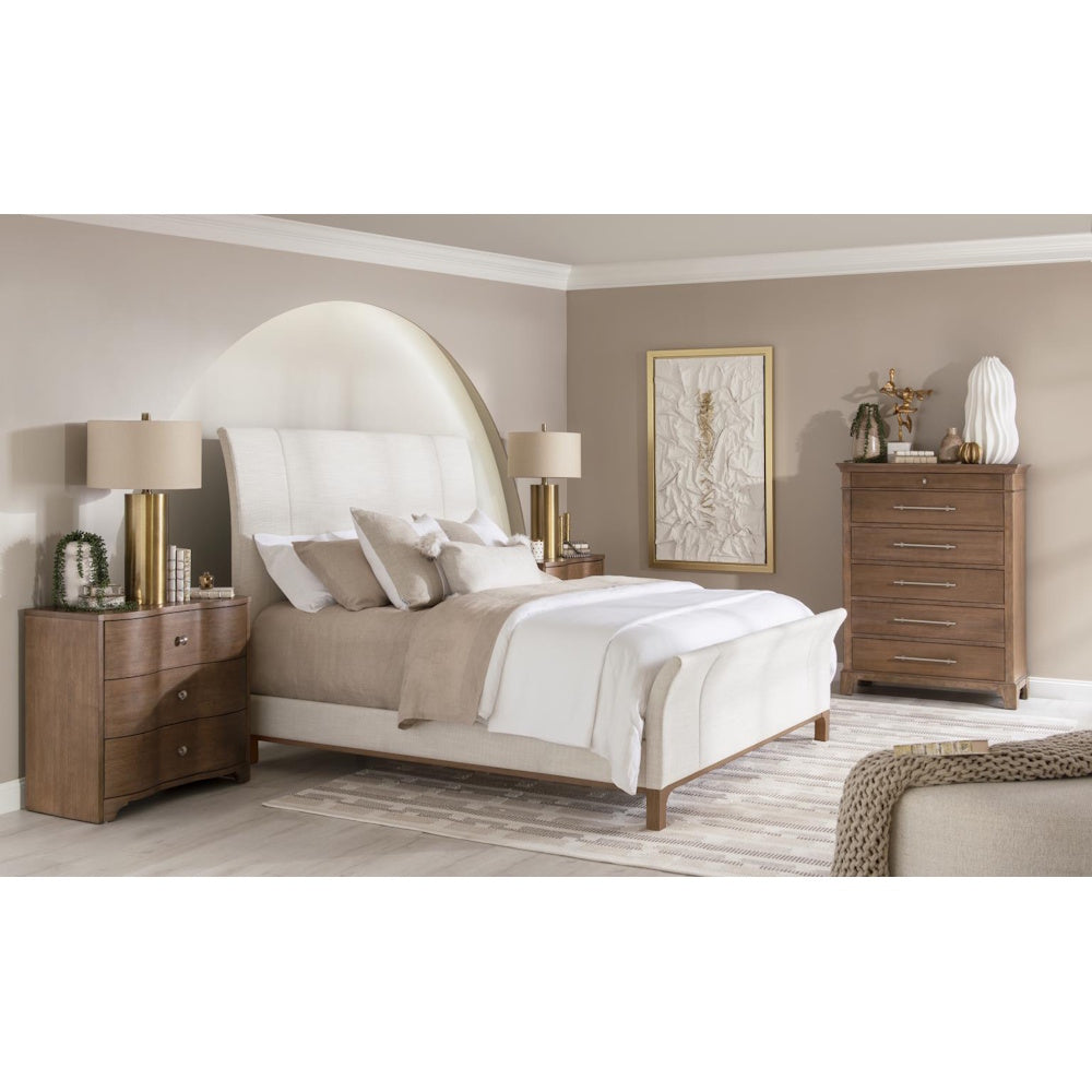 Modern neutral bedroom set with upholstered bed, wood dresser, and gold nightstand lamps.