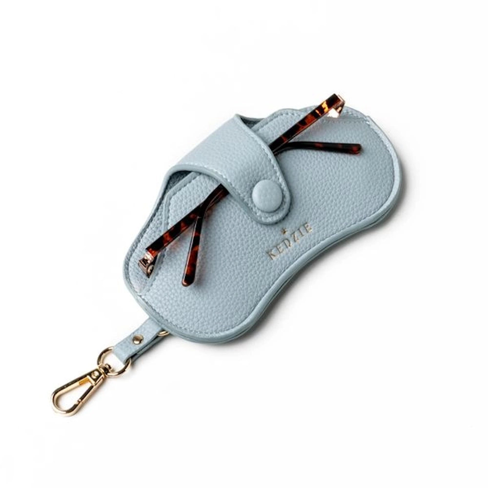 Light blue Kedzie Eclipse pebble leather eyewear case with tortoise shell glasses and a gold lobster claw keychain clip.