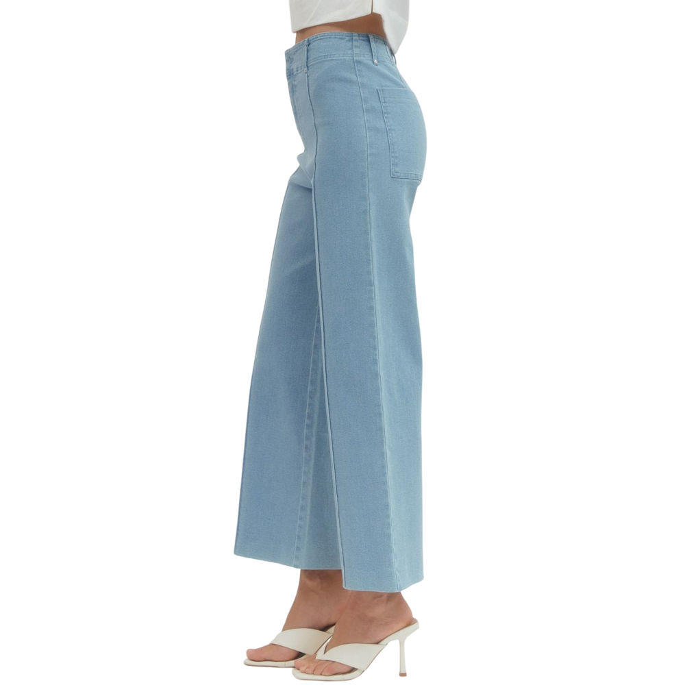 Side view of a person wearing light blue high-rise, wide-leg pants and cream heeled sandals.