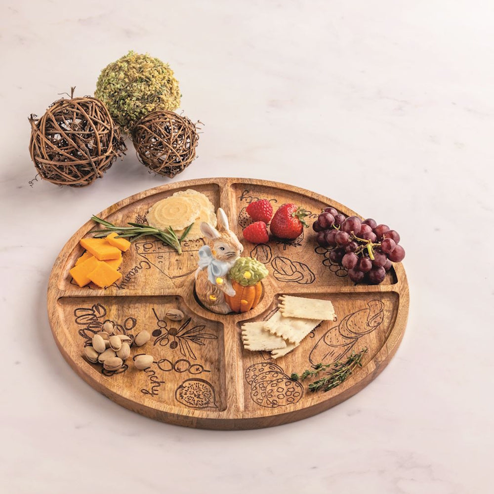 Round wooden charcuterie board with five sections, featuring a center bunny sitter, fruit, nuts, cheese, and crackers.