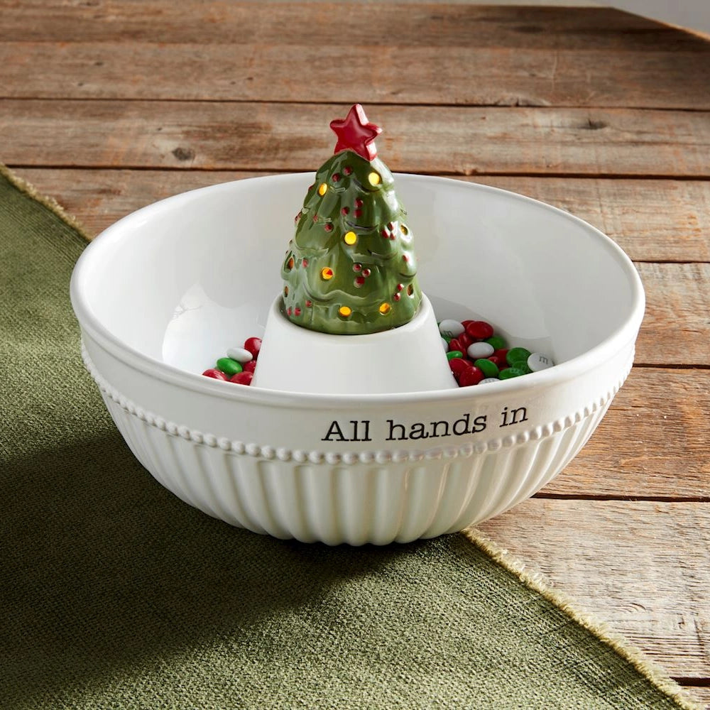 Light-up ceramic Christmas tree sitter in a white snack bowl filled with holiday candies.
