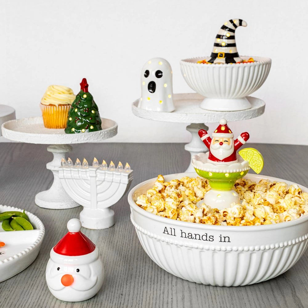 Holiday table display with ceramic sitters, a popcorn bowl, cake stands, and festive decor.