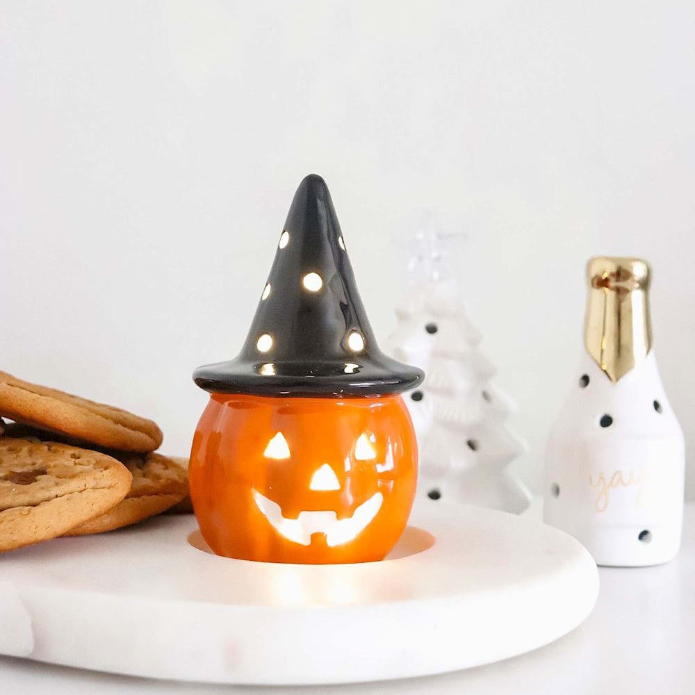 Light-up ceramic witch jack-o'-lantern Halloween decoration sitting on a white tray with cookies.