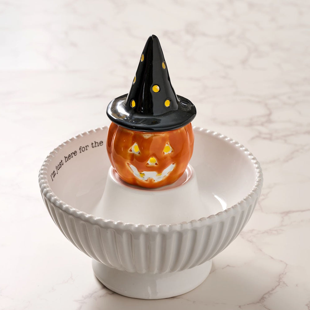 Ceramic witch hat jack-o'-lantern sitting inside a white Halloween candy serving bowl.