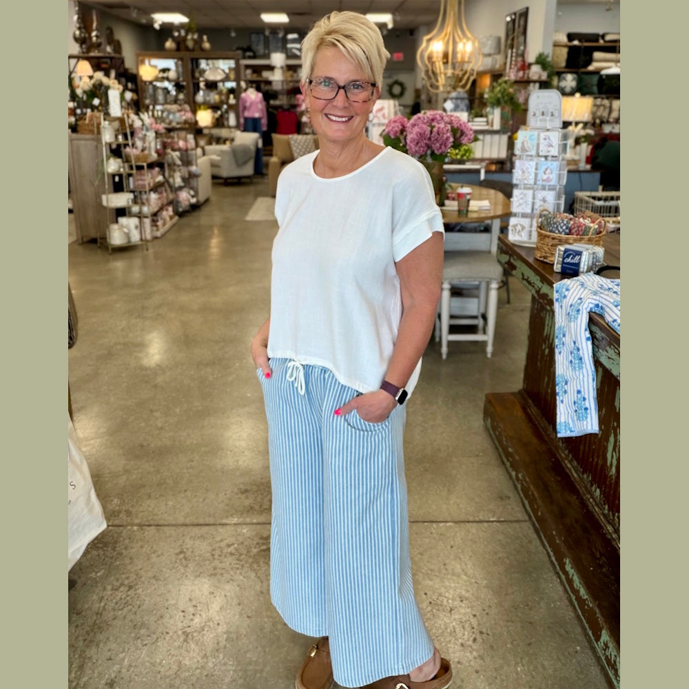 Woman in white top and light denim stone wash stripe wide-leg pants.