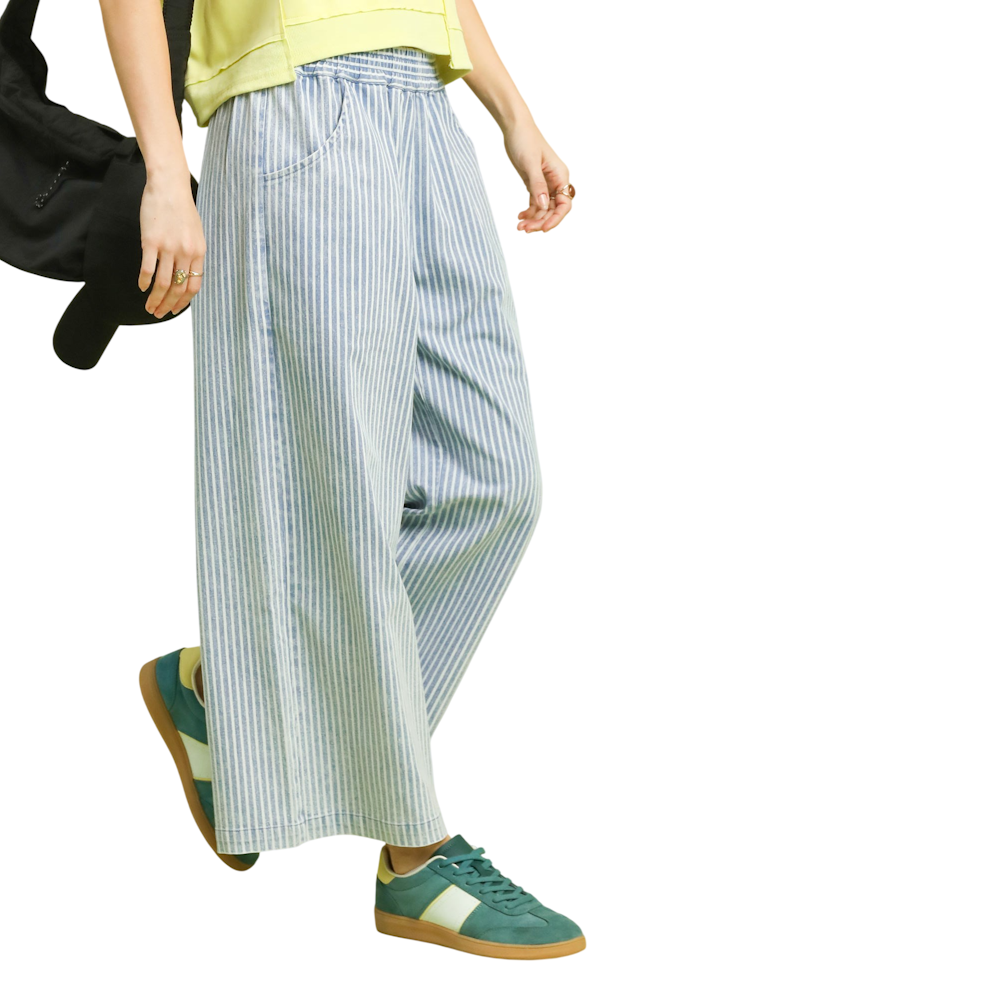 Side view of light denim stone wash vertical stripe wide leg pants with pockets, styled with green sneakers.