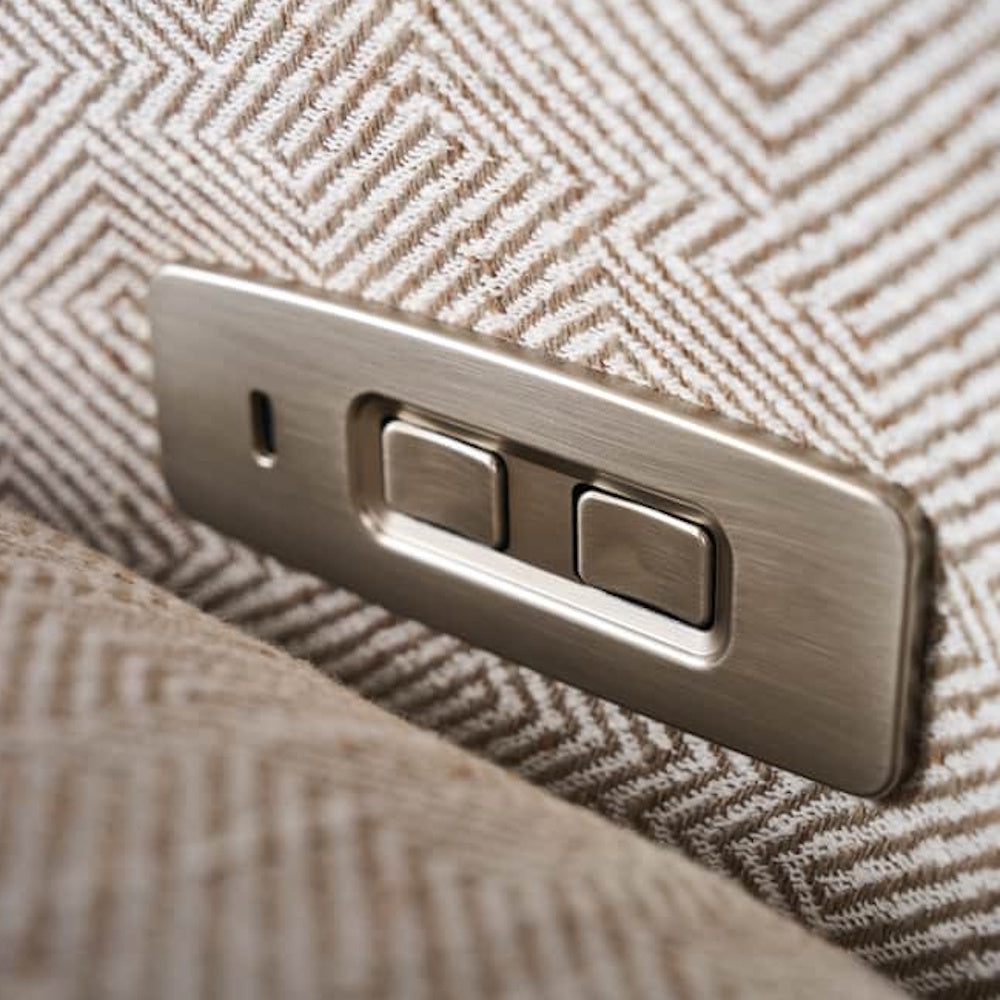 Close-up of a brushed metal power recliner control panel with USB port on textured chevron pattern upholstery.