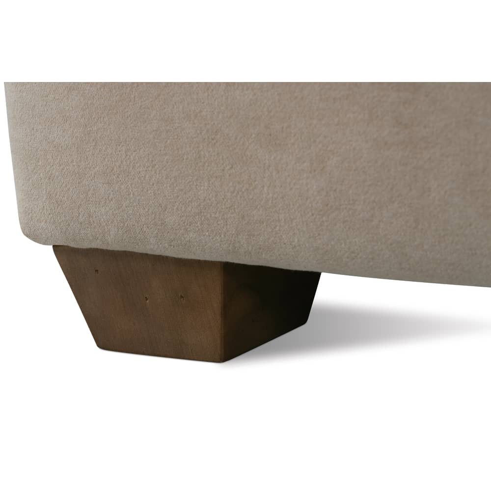 Close-up of a modern beige upholstered sofa with a chunky tapered wooden leg on a white background.