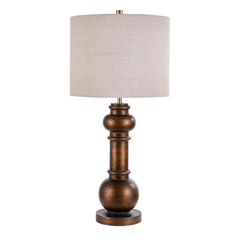 Antique bronze table lamp with a cream drum shade and a traditional sculpted pillar base for living room decor.