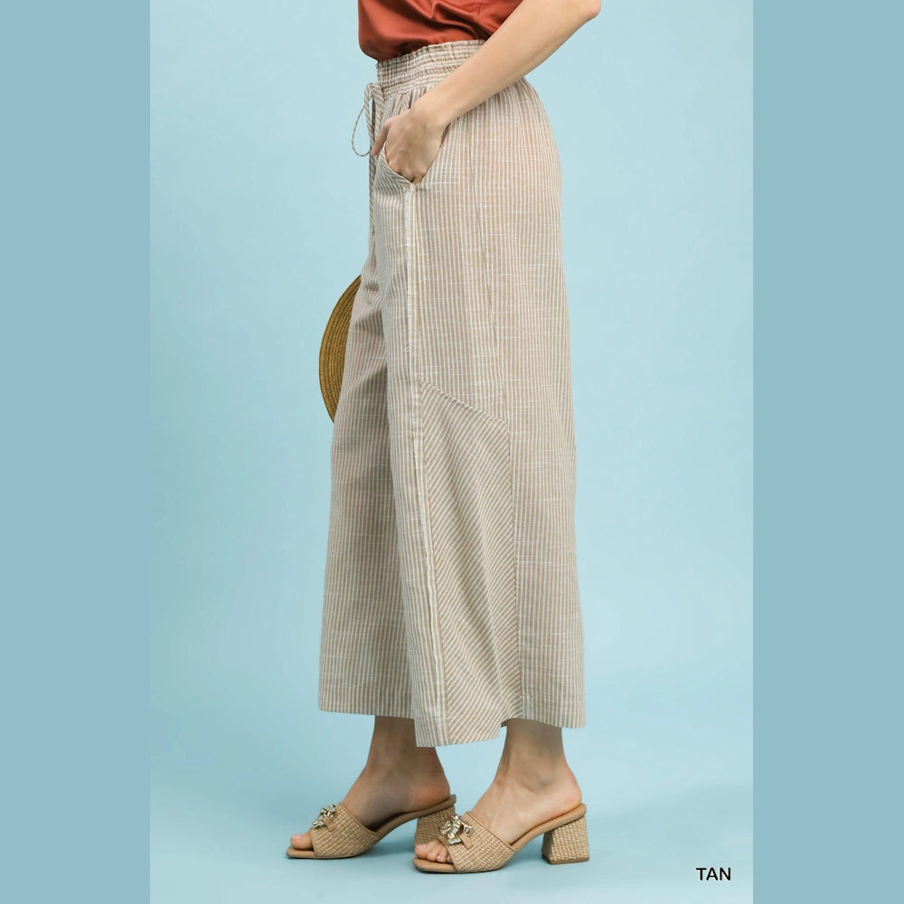 Tan linen-blend striped wide-leg pants with a drawstring waist and side pockets styled with block-heeled sandals.