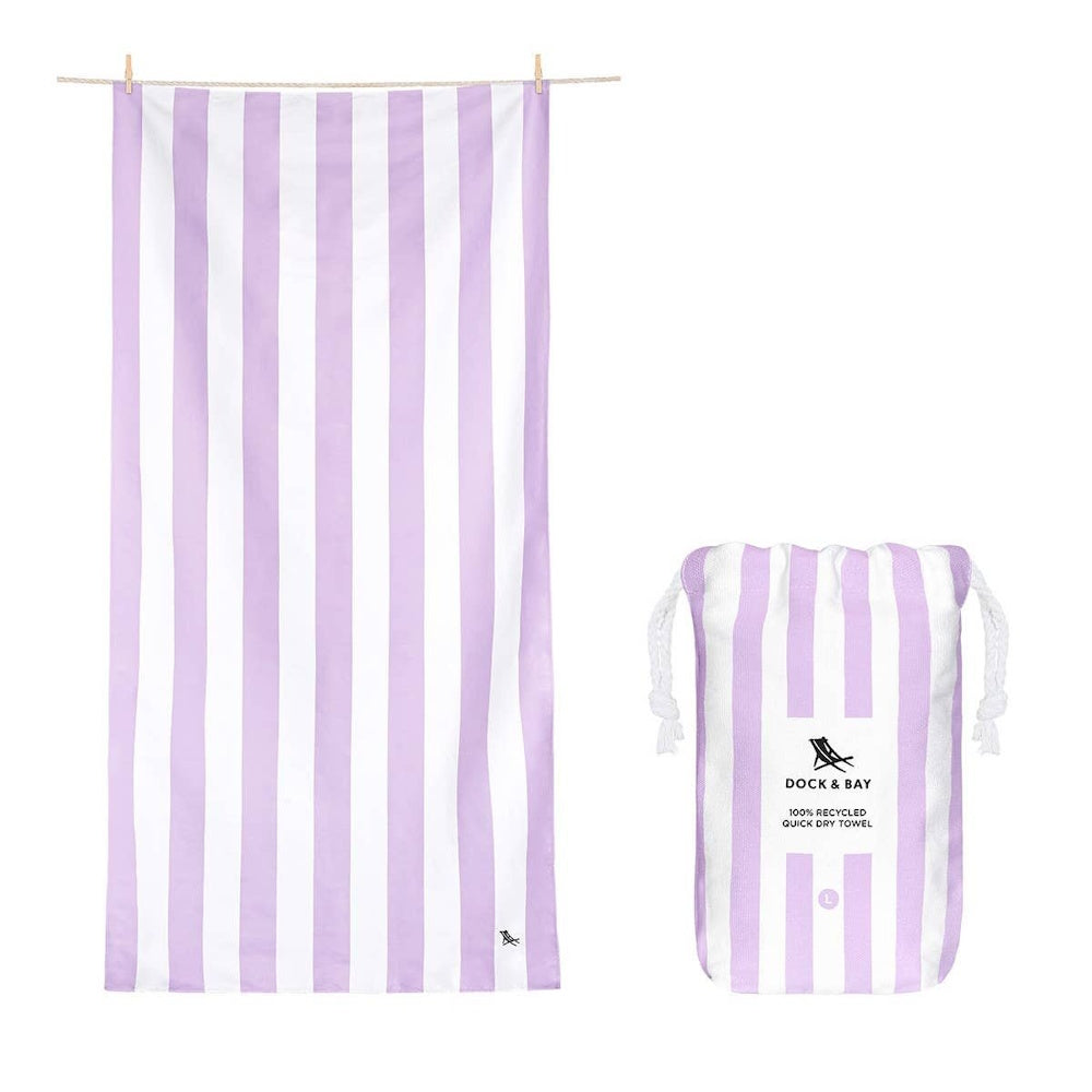 A lilac and white striped beach towel hanging up, next to its matching drawstring storage pouch.