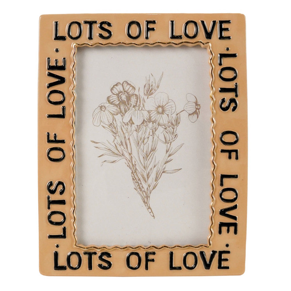 A tan ceramic frame embossed with "LOTS OF LOVE" in black text, holding a sketch of a flower bouquet.