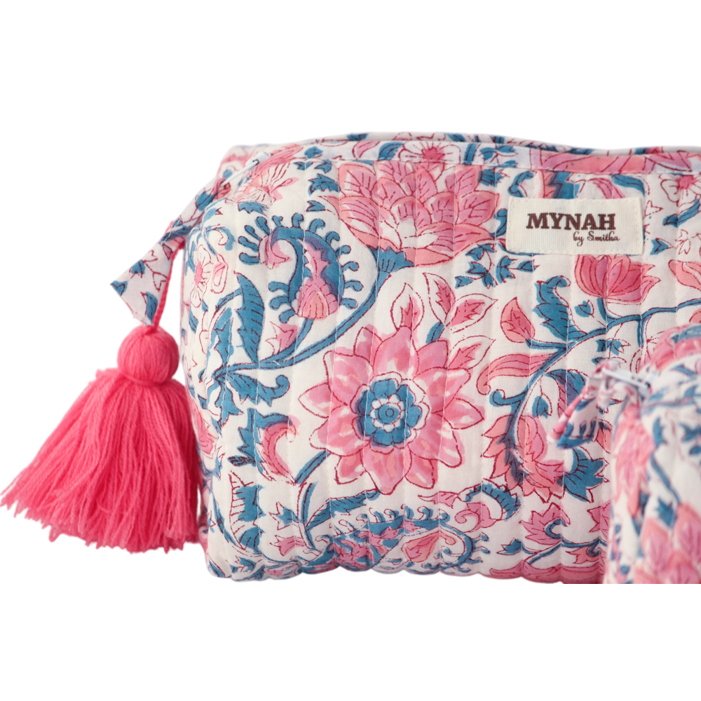 Close-up of a white quilted zipper pouch featuring a pink and blue floral lotus print and a pink tassel.