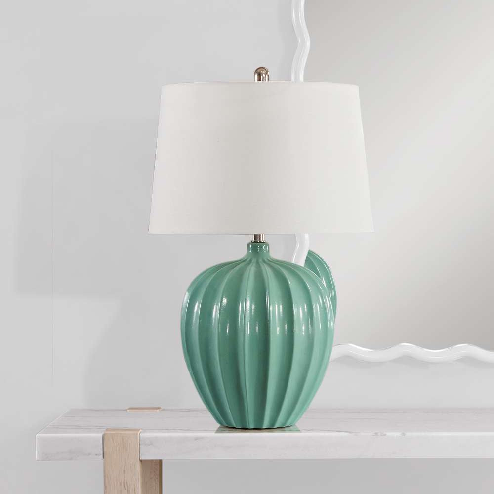 Modern mint green ribbed ceramic table lamp with a white drum shade on a marble console table.