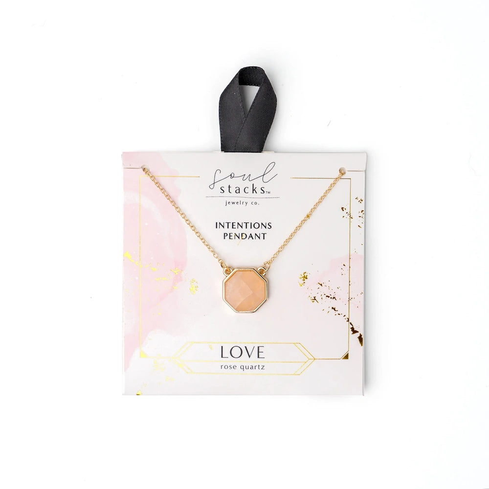 Soul Stacks Rose Quartz Love Intentions Pendant on a gold chain, displayed on pink watercolor themed packaging.
