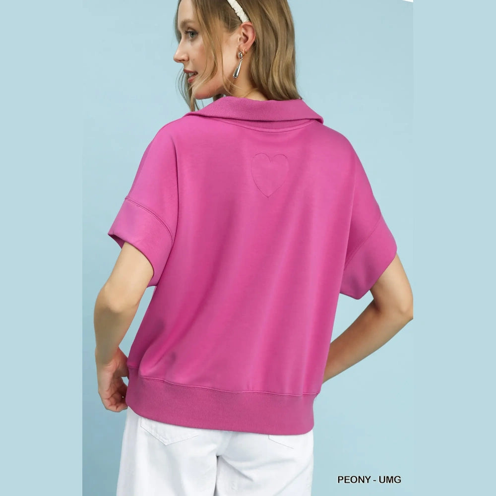 Back view of a woman in a Peony pink luxe knit half-zip pullover featuring a subtle stitched heart detail on the back.