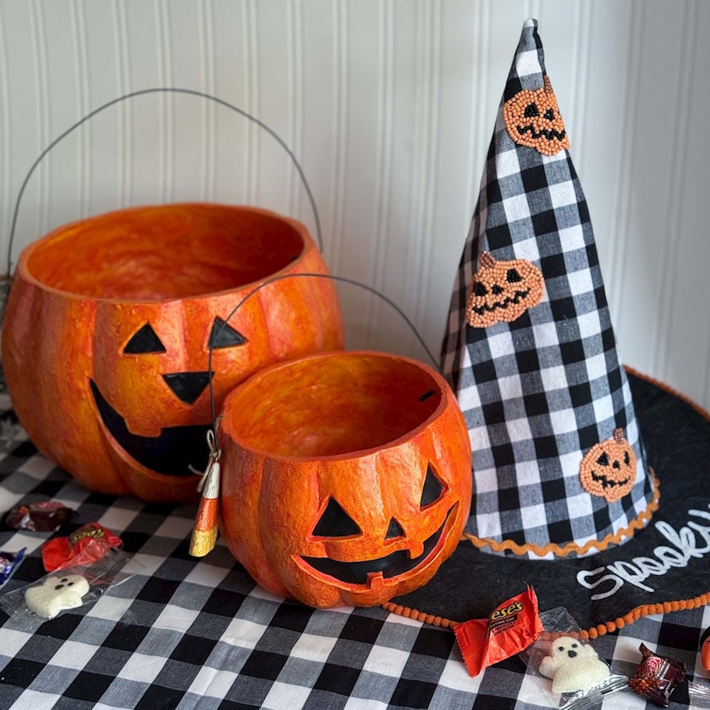 Two orange jack-o-lantern treat buckets and a plaid witch hat.