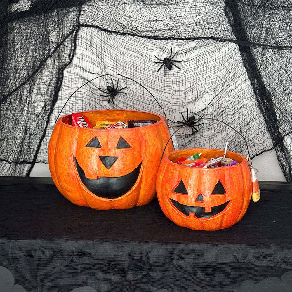 Two jack-o'-lantern candy buckets filled with Halloween treats.
