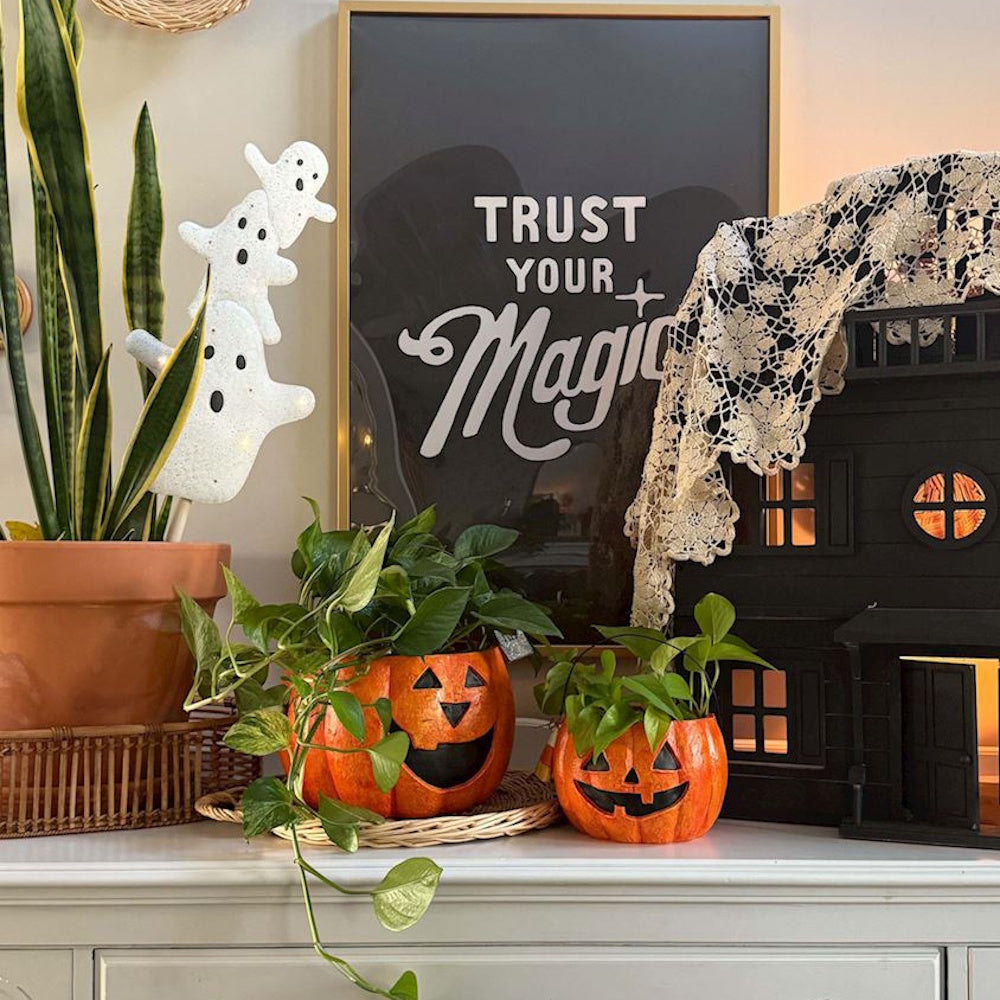 Halloween jack-o'-lantern buckets used as indoor plant pots for home decor.