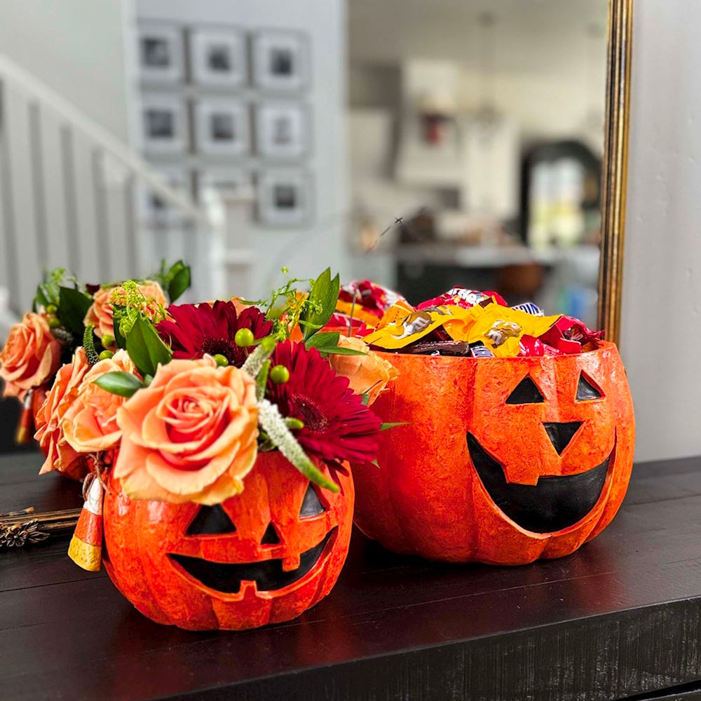 Halloween pumpkin buckets filled with flowers and candy.
