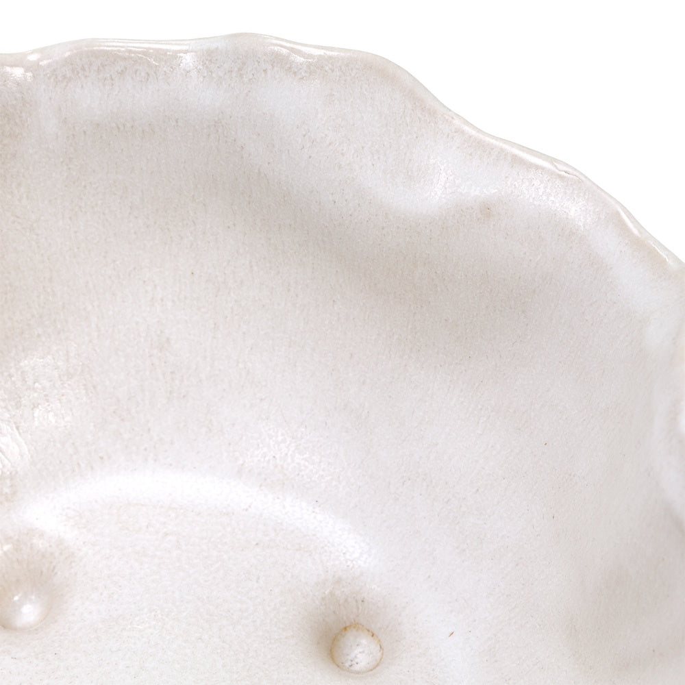 Close-up of the Magnus wavy-rimmed beige ceramic bowl interior showing a textured glaze finish and two small internal feet.