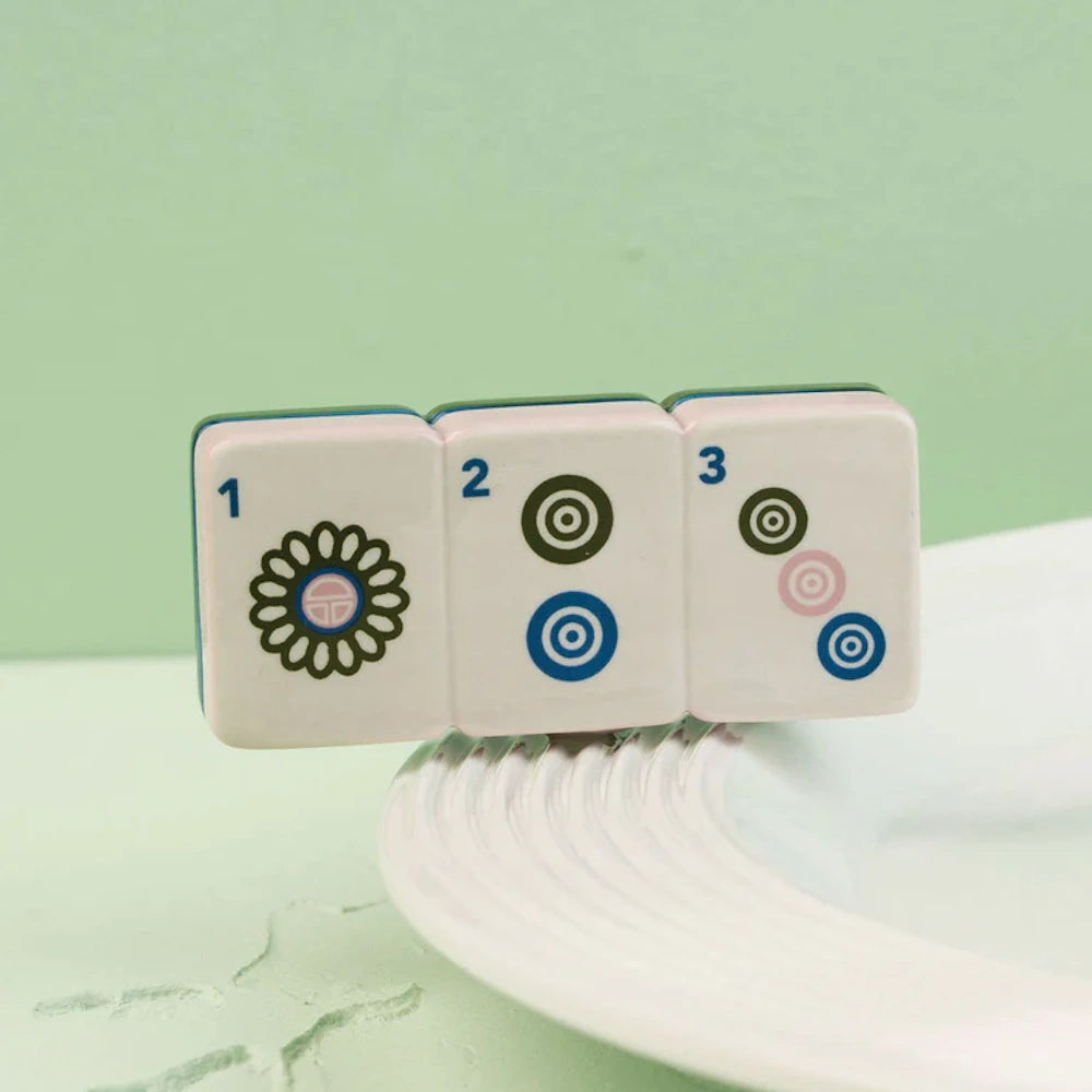 Small ceramic charm featuring three connected mahjong tiles numbered 1, 2, and 3 resting on a dish rim.
