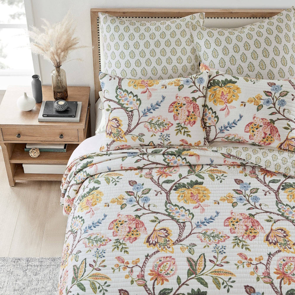 Maileen floral quilt set with matching pillow shams in yellow and pink on a white quilted background.